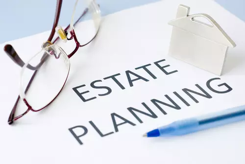 Estate planning written on paper with eye glasses and pen.