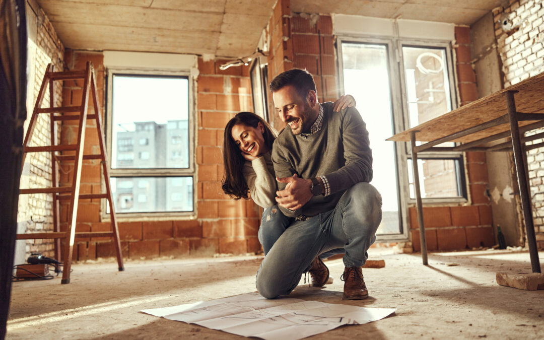 Young happy couple examining blueprints during home renovation process in the apartment.